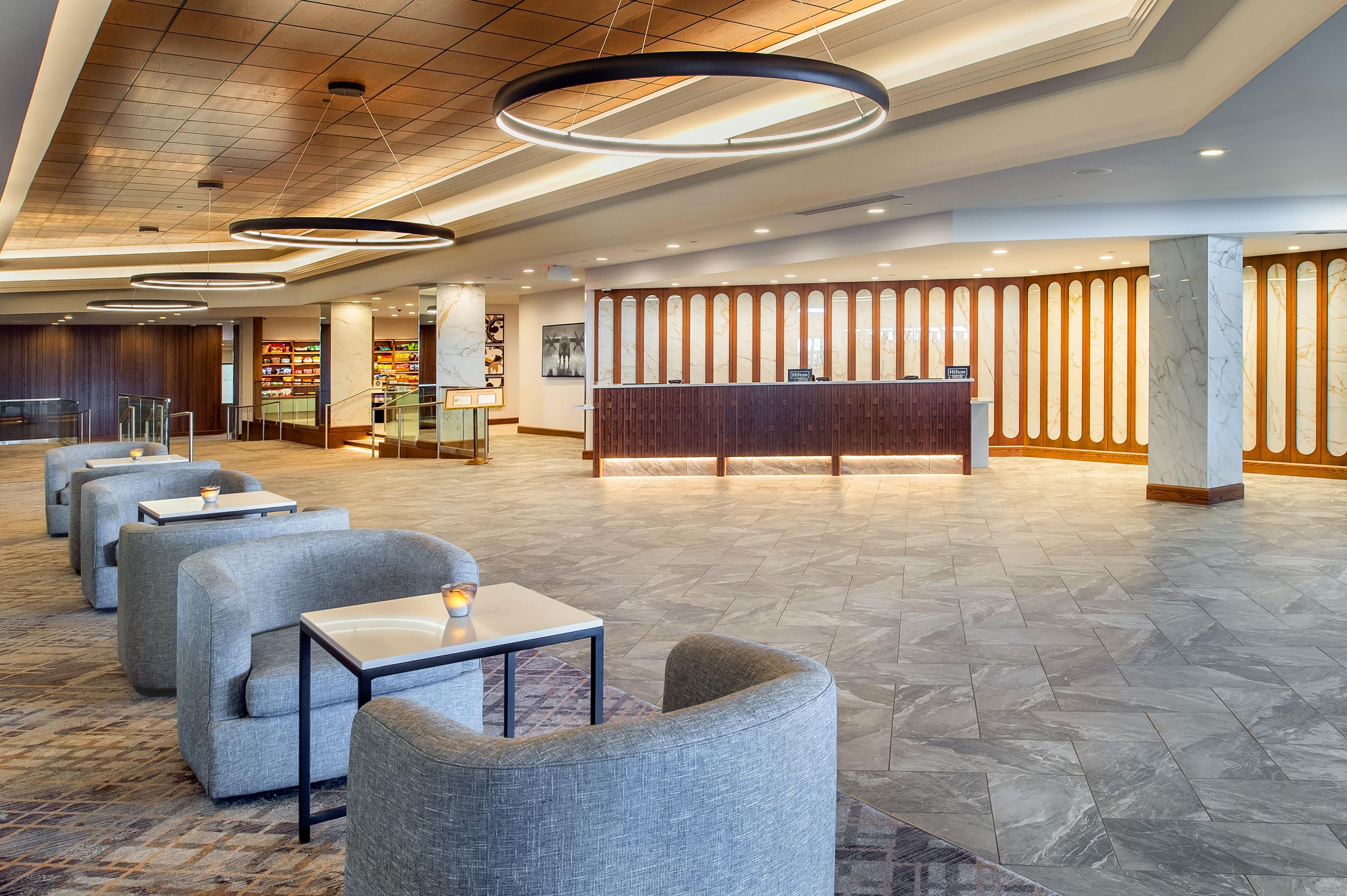 Un vestíbulo de hotel con mostrador de recepción, zona de estar y exhibición de alimentos.
