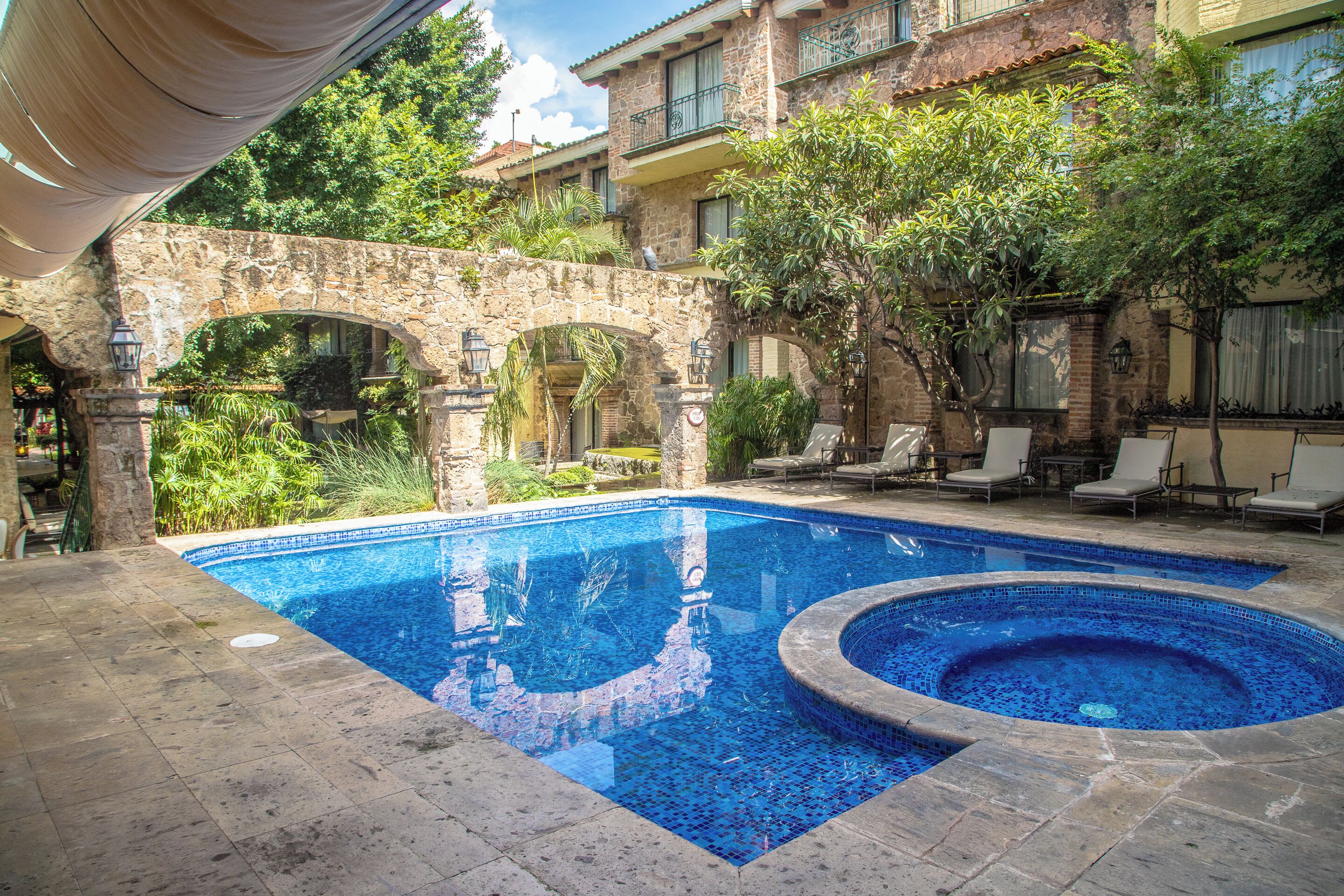 Una piscina al aire libre, sombrillas, sillones reclinables de piscina