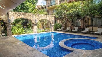Una piscina al aire libre, sombrillas, sillones reclinables de piscina