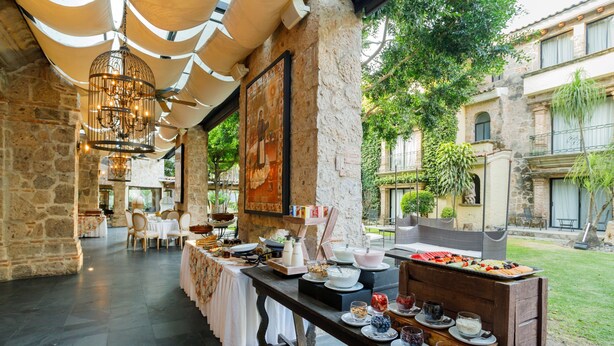 Comedor con una larga mesa dispuesta para un bufé, rodeado de paredes de piedra y una lámpara colgante.