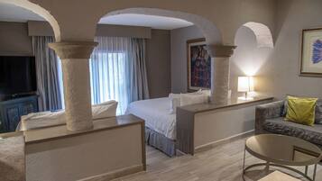 Una habitación de hotel con una cama, televisión, sofá y mesa.
