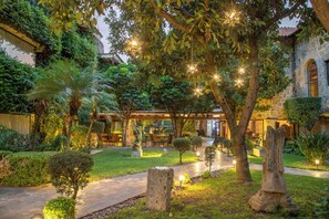 Un patio con sendero de piedra, árboles y mobiliario exterior.