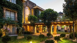 Un patio con un edificio de piedra, una estatua y una zona de estar cubierta.