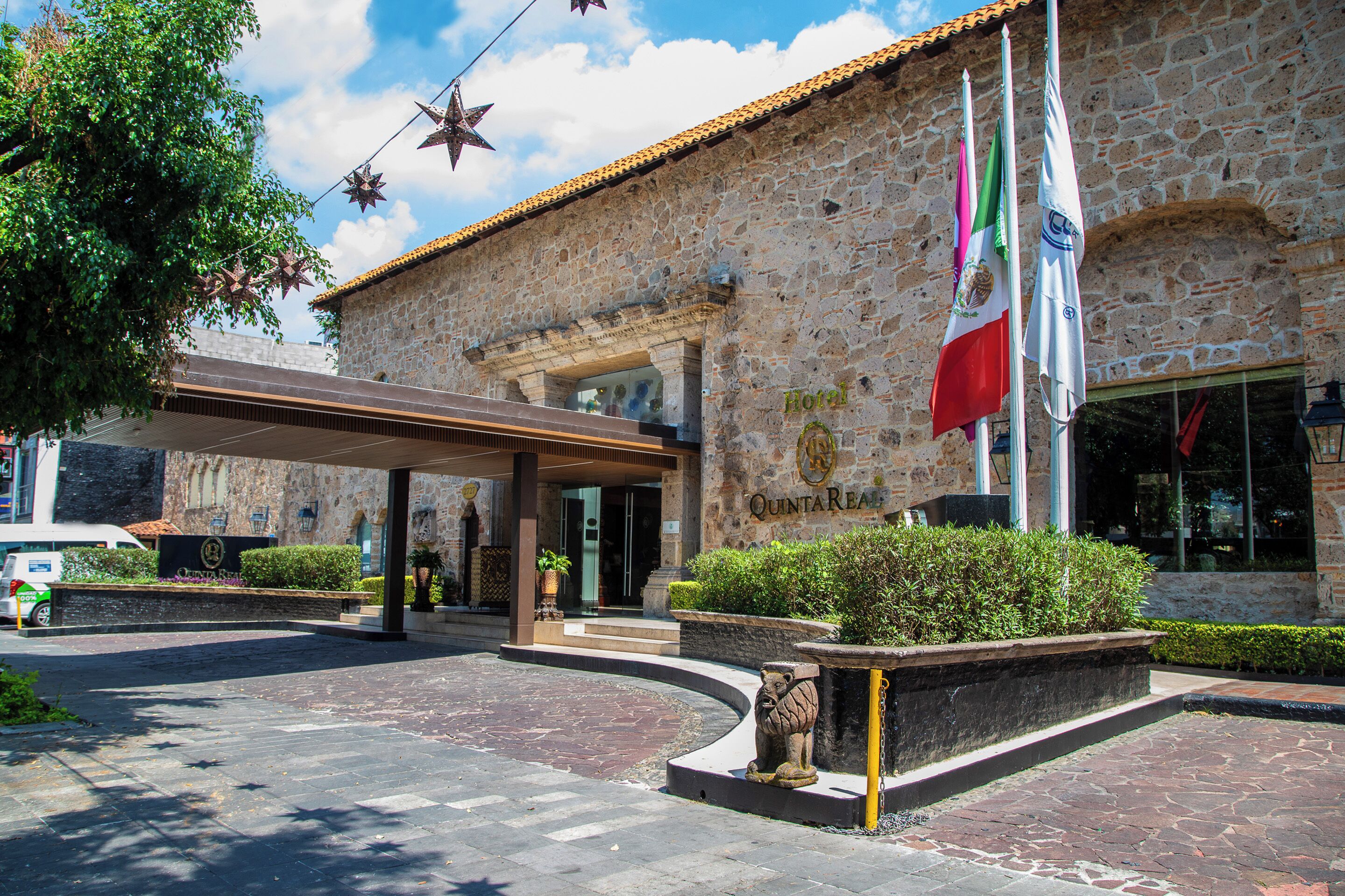 A stone building with a covered entrance, a flag, and a lion statue.