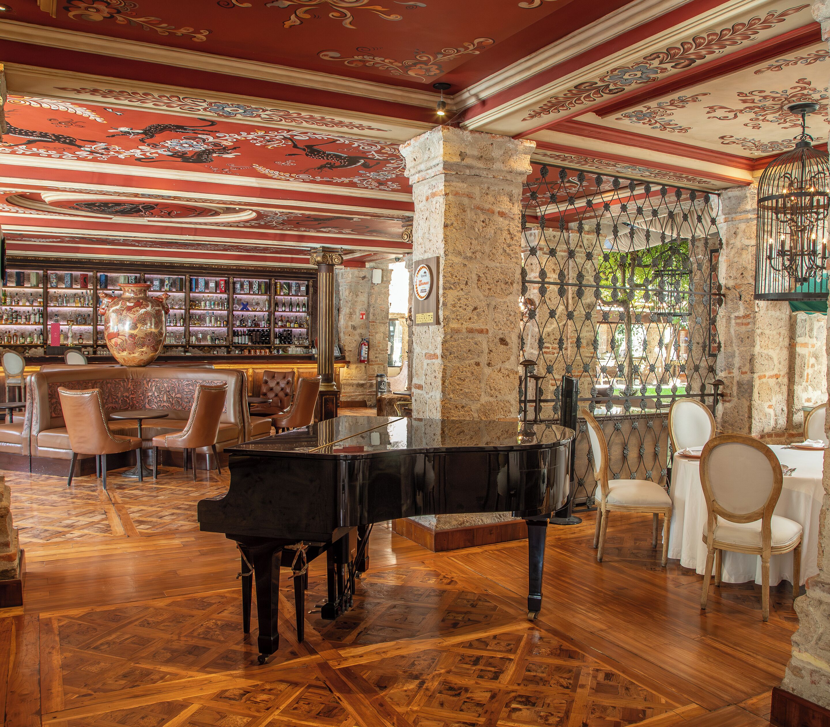 Zona de bar con piano, asientos y estante para vinos.