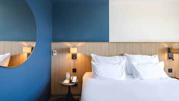 A hotel room with a large bed, a round mirror, and a wall-mounted telephone.