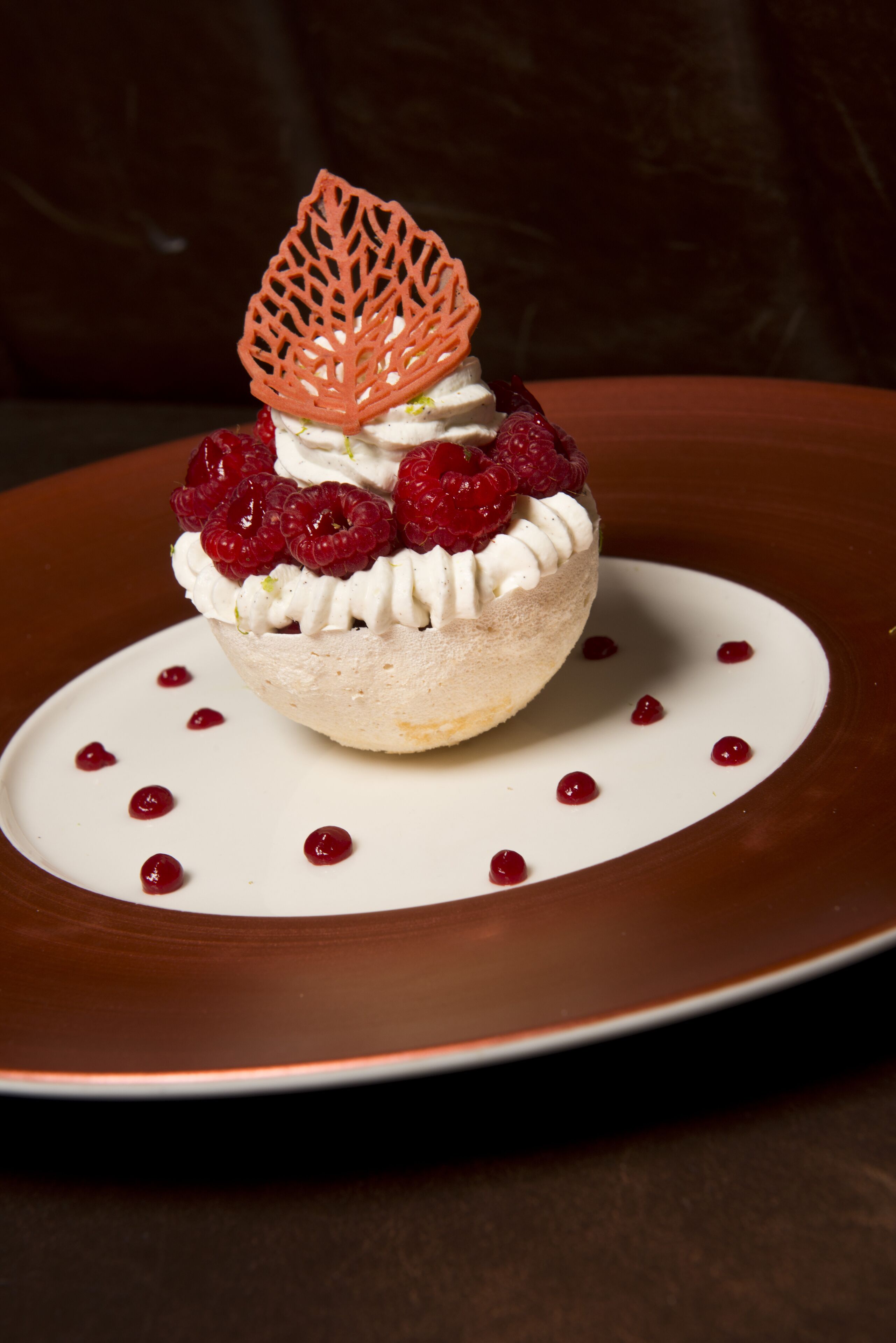 Un dessert présenté dans une assiette, orné d’une feuille décorative sur le dessus.