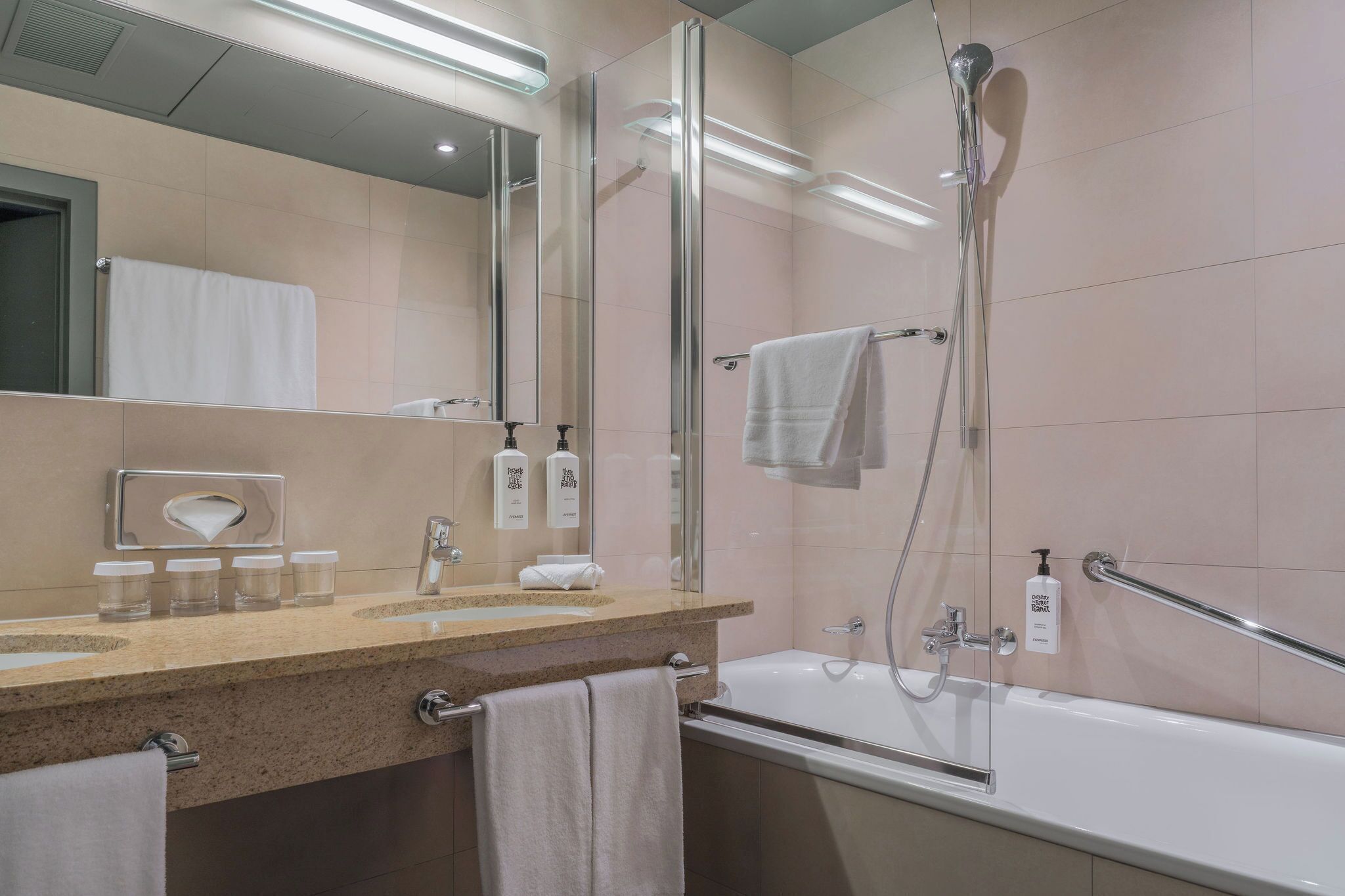 A modern bathroom with a glass shower enclosure, a bathtub, a vanity with a mirror, and a towel rack.