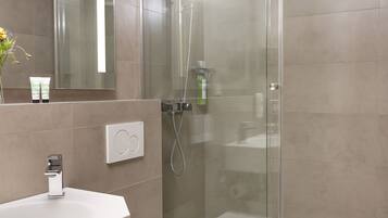 A modern bathroom with a glass-enclosed shower, a white sink, and a toilet.