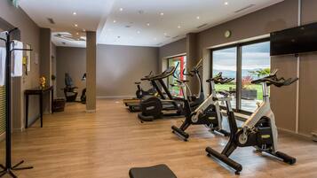 A gym with cardio machines, a bench, and a large window offering a view.