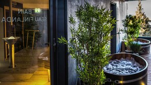 A glass door entrance with a bamboo plant and a hot tub outside.