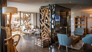 A modern living room with lounge chairs, a wooden decorative wall, a television, and a bookshelf.