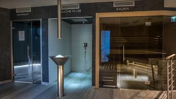 Experience the serene ambiance of our Hammam area, featuring a glass-enclosed space with a shower and central column.