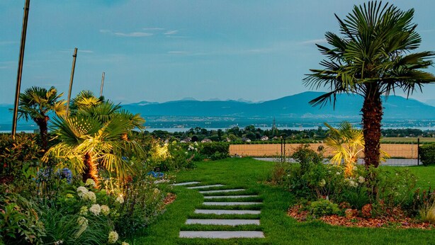 A garden pathway leading to a view of a city and mountains.