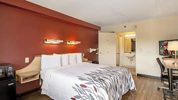 Une chambre d’hôtel comprenant un lit, une table de chevet, une lampe et un bureau avec une chaise.