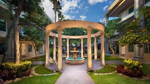 Un pabellón circular con una fuente central, rodeado de un jardín cuidado y senderos.