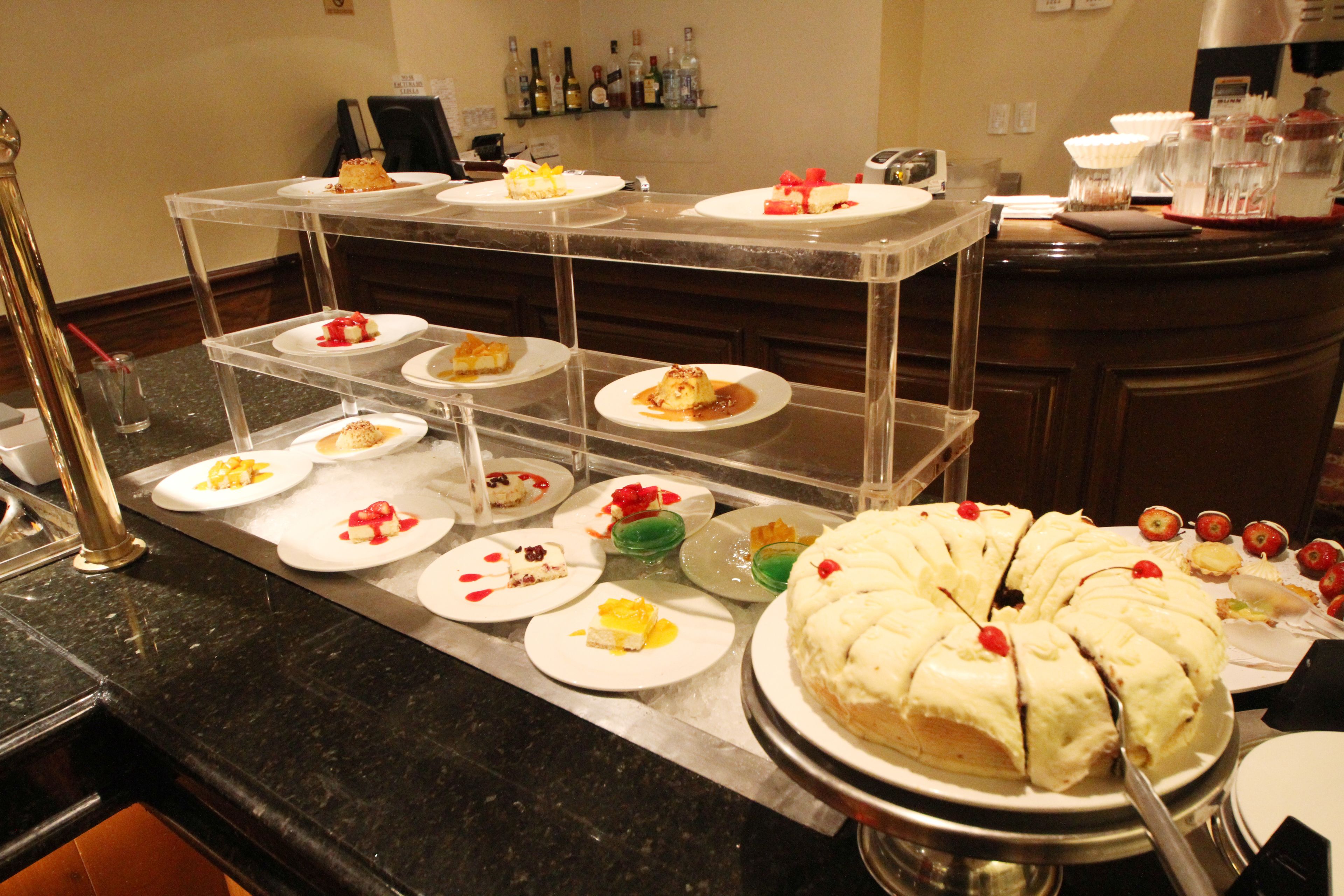 A buffet with various desserts on display, including a large cake with a cherry on top.