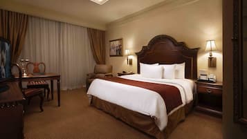 Habitación de hotel con una cama grande, un escritorio, una silla y una mesita de noche con lámparas.