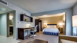 Ett hotellrum med en säng, ett skrivbord, en stol och en liten sittgrupp.
