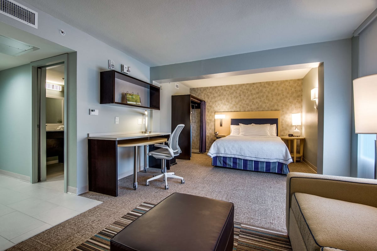 Habitación de hotel con cama, escritorio, silla y un pequeño rincón de descanso.