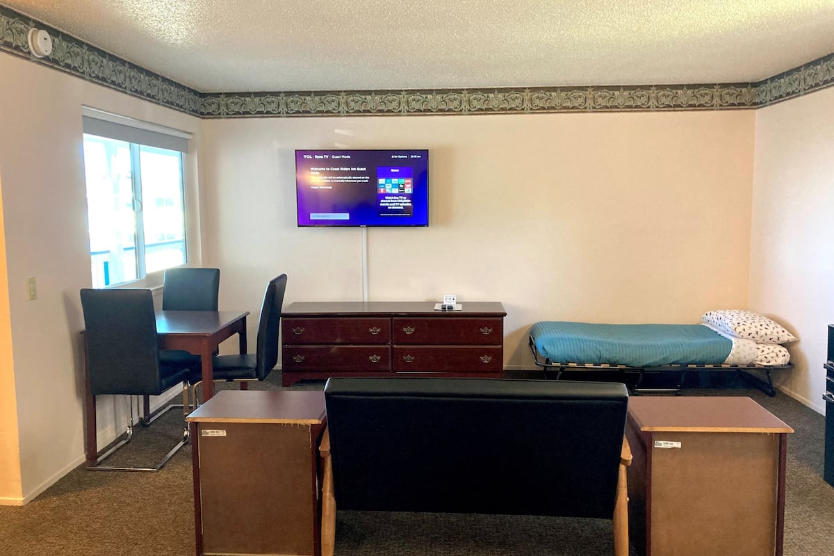 Habitación de hotel con escritorio, silla, televisor, cama y cómoda.