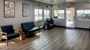 Uma área de espera com uma motocicleta, um banco e cartazes nas paredes.