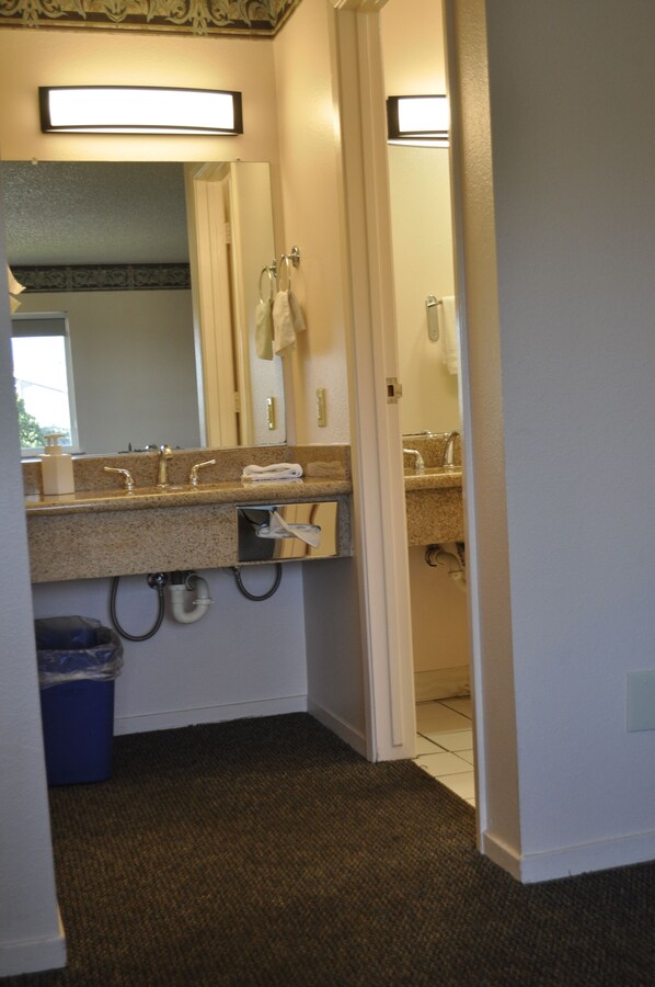 A bathroom with a sink, mirror, towel rack, and a trash bin.