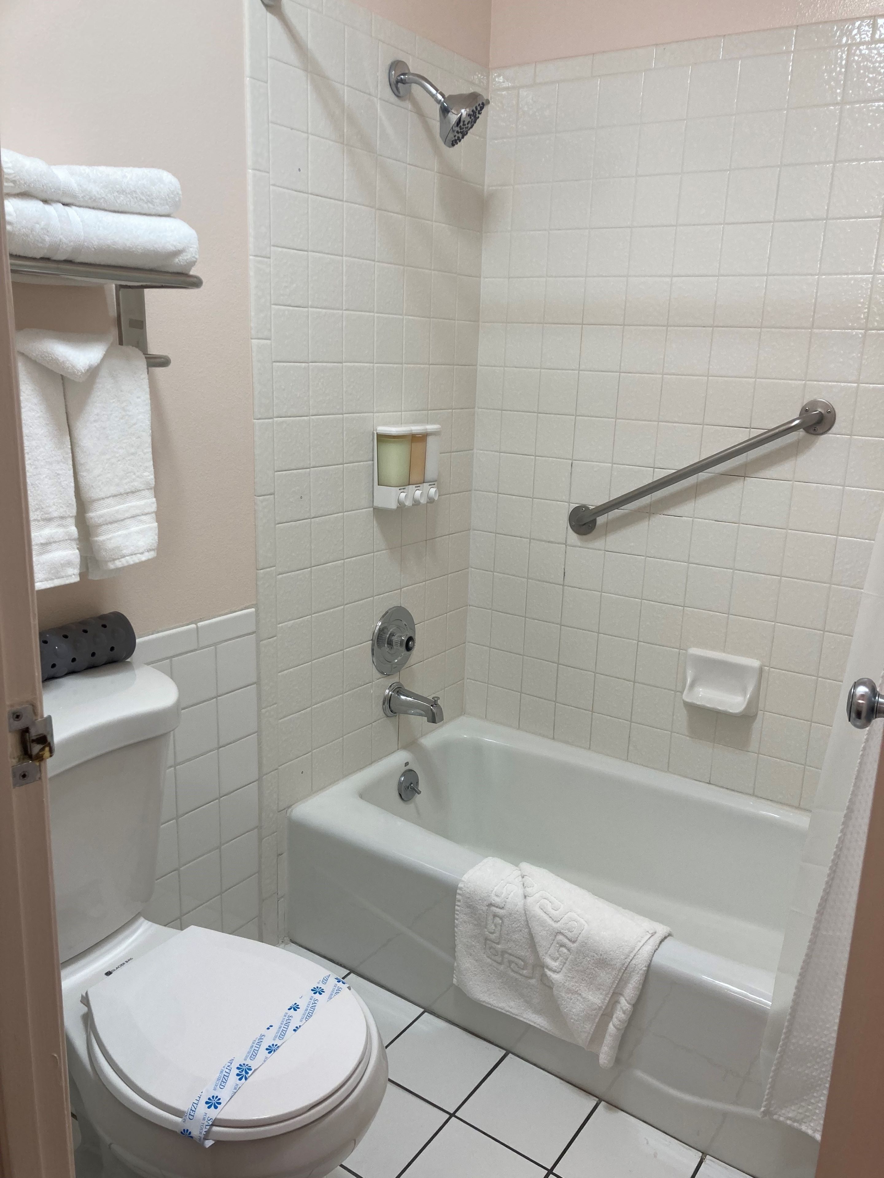 Un baño con inodoro, bañera, ducha y un perchero para toallas.