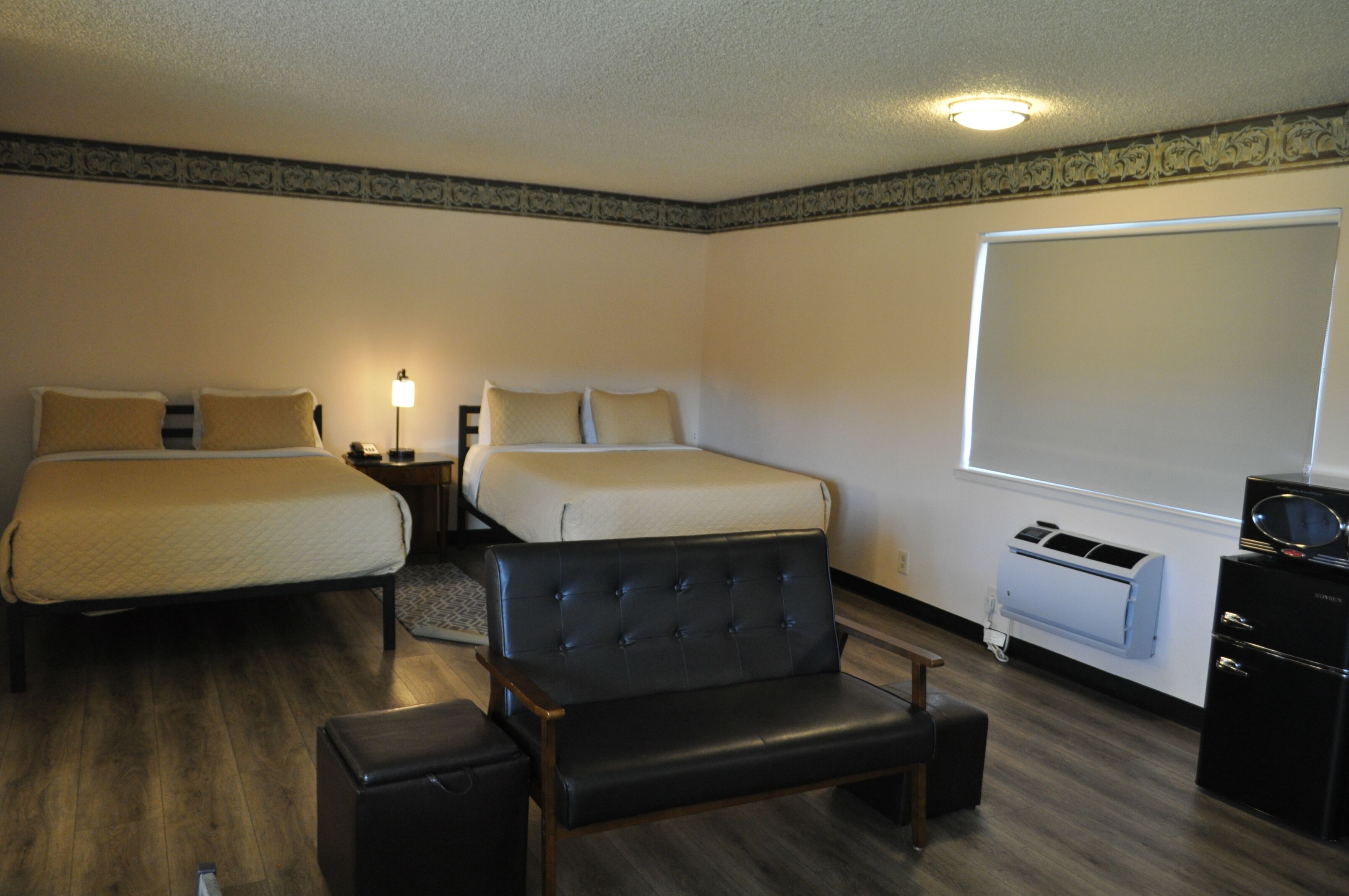 Een hotelkamer met twee bedden, een zwarte leren fauteuil, een bureau en een minibars.