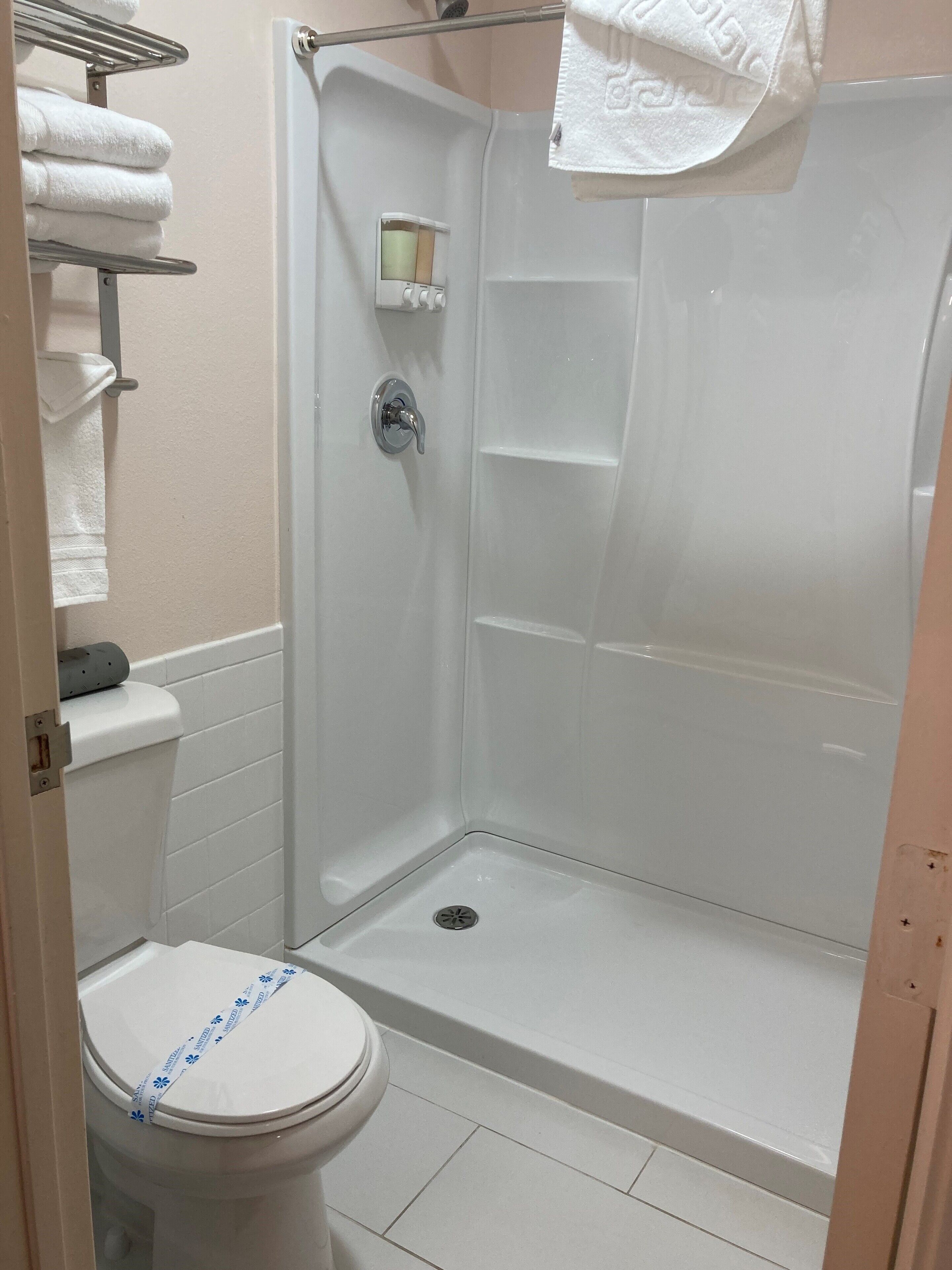 A small, enclosed shower stall with a toilet and a towel rack.