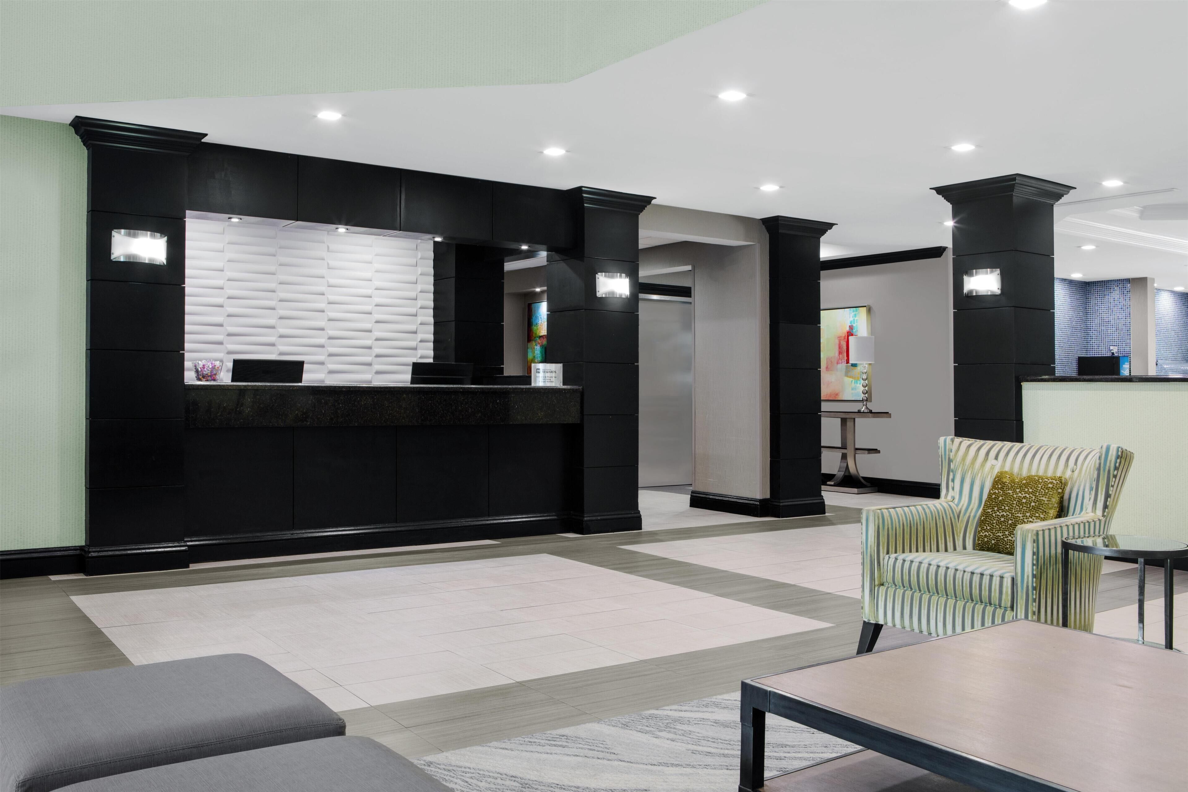 A reception area with a black reception desk, a seating area with a sofa and armchairs, and a small table.