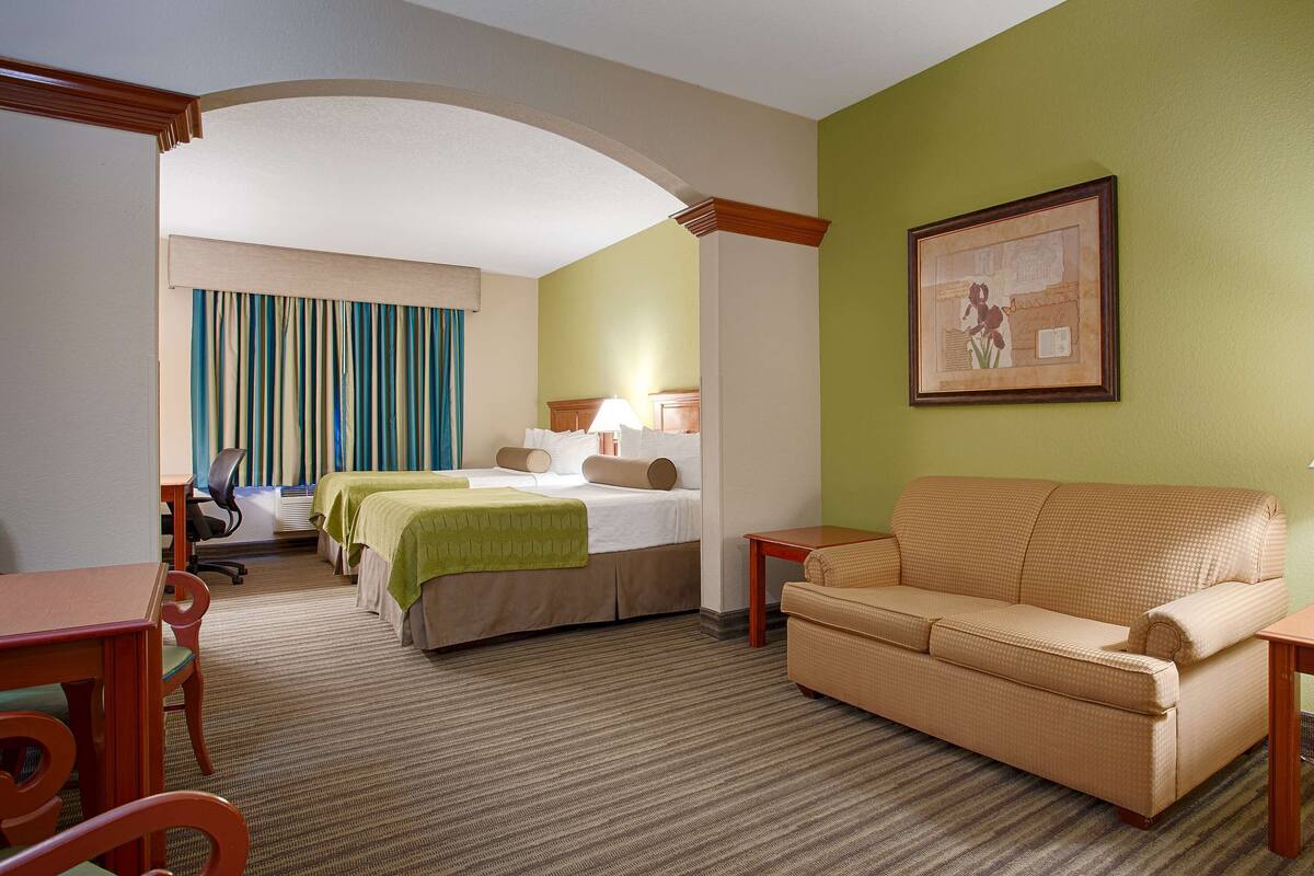 Une chambre d’hôtel avec un lit, un canapé, un bureau et une lampe.
