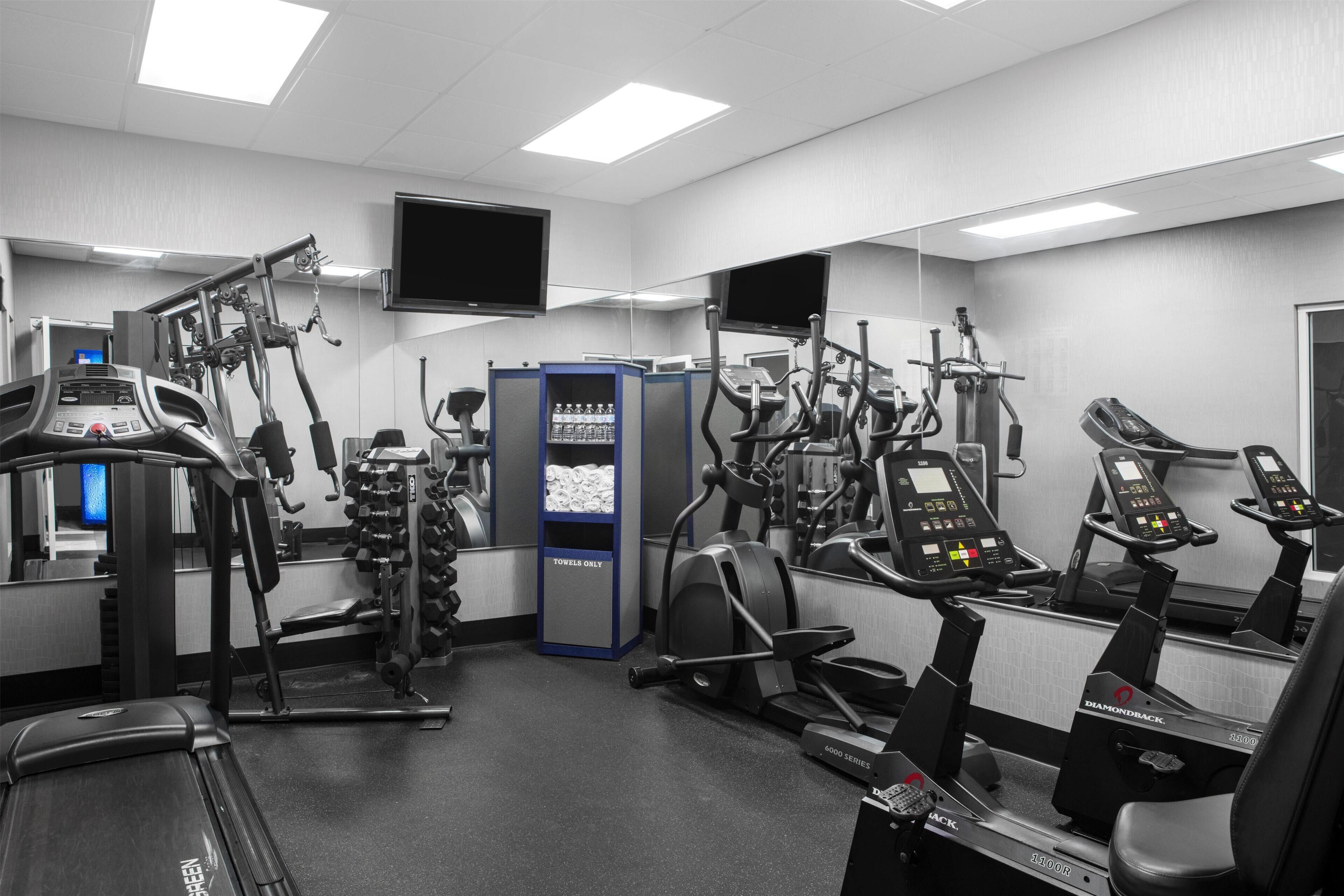 A gym with various exercise equipment, including treadmills and weight machines, and a water dispenser.
