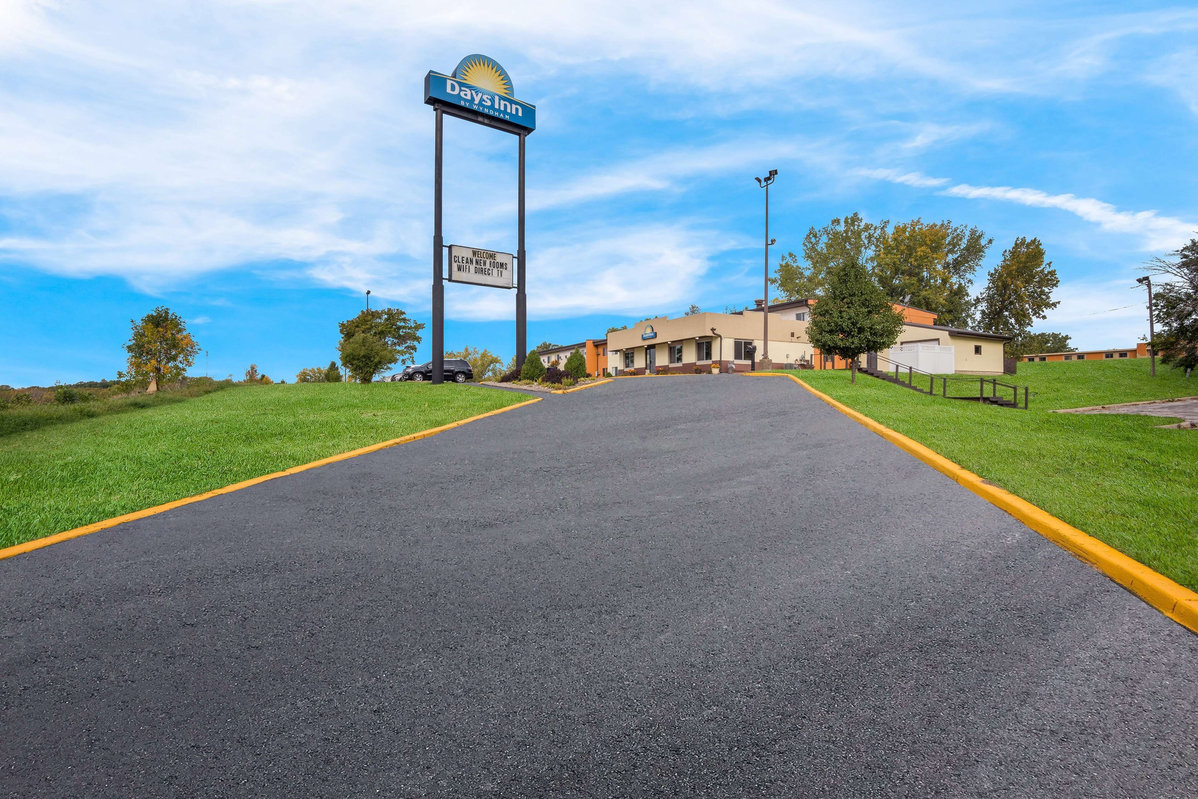 A Days Inn sign, a parking lot, and a building with a flat roof and beige walls.