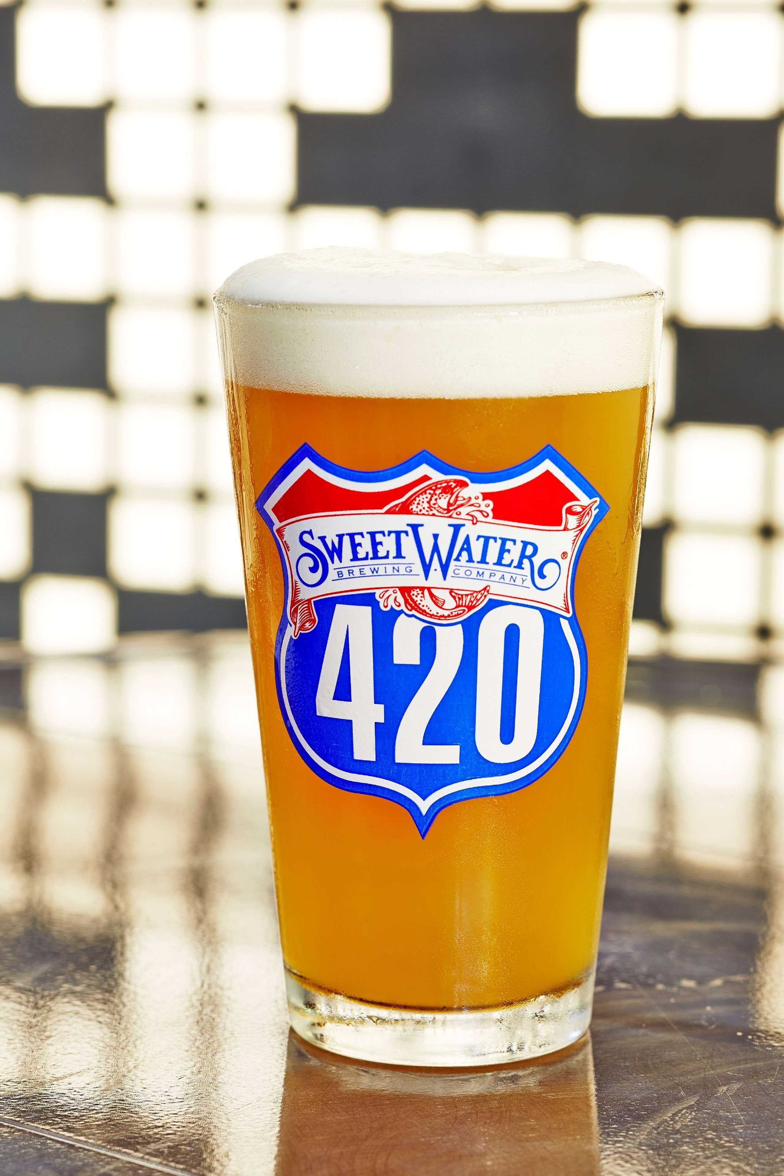 A glass of beer with a label reading "Sweet Water Brewing Company 420".