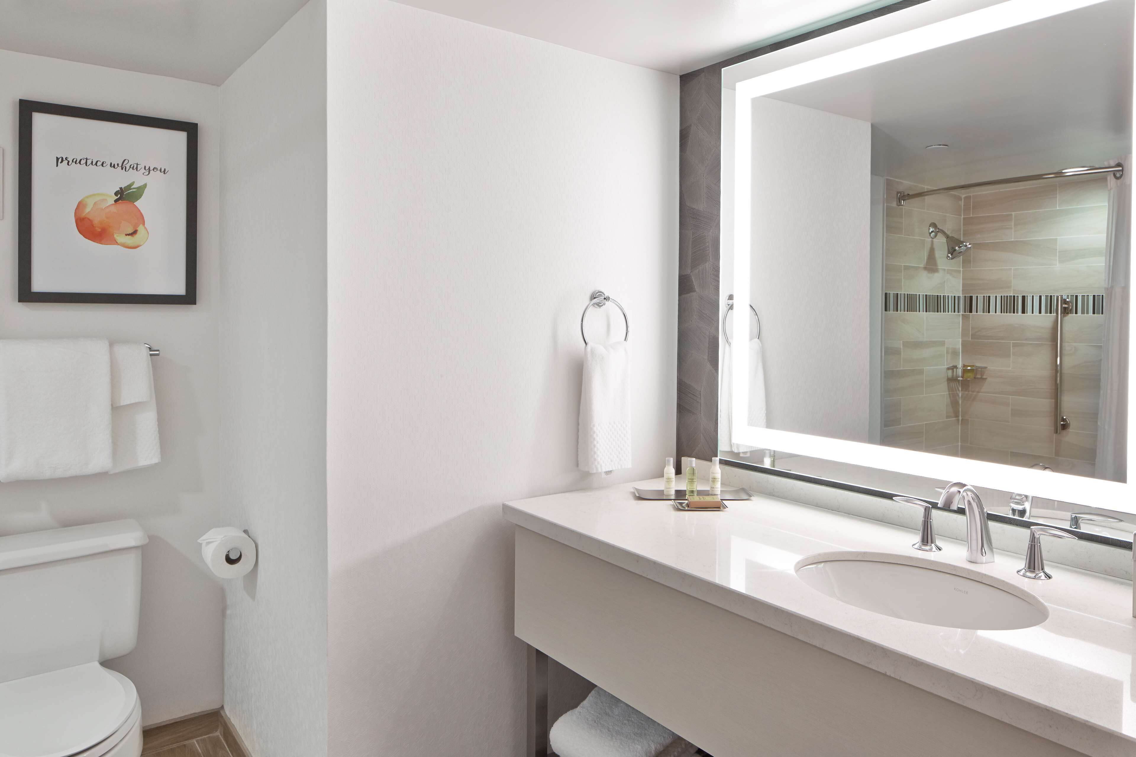 A modern bathroom with a large mirror, a sink, and a toilet.