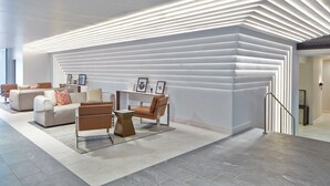 A modern lobby with a geometric light installation on the wall, a seating area with sofas and a coffee table, and a staircase with a metal railing. - DoubleTree by Hilton Atlanta Perimeter Dunwoody (Atlanta)