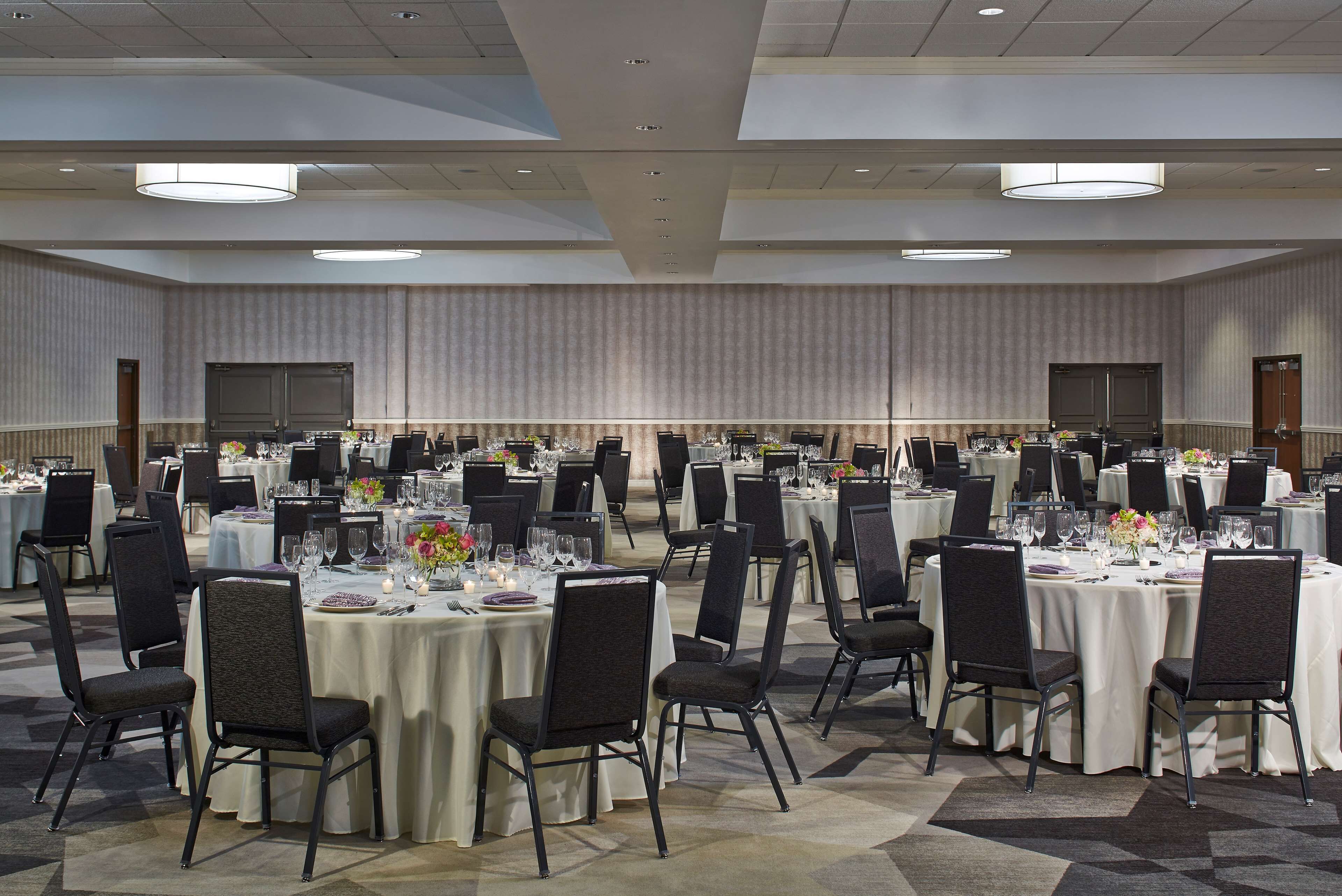 A large banquet hall with round tables set for dining, equipped with chairs and table settings.