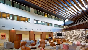 A spacious lobby with multiple seating areas, a flat-screen TV mounted on the wall, and a patterned wall feature. - DoubleTree by Hilton Atlanta Perimeter Dunwoody (Atlanta)