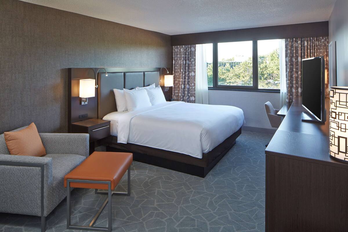 A hotel room with a large bed, a sofa, a desk, and a TV.