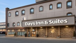 A Days Inn & Suites building with a stone facade, large windows, and a visible hotel parking area. - Days Inn & Suites by Wyndham Sault Ste. Marie ON (Sault Ste. Marie)