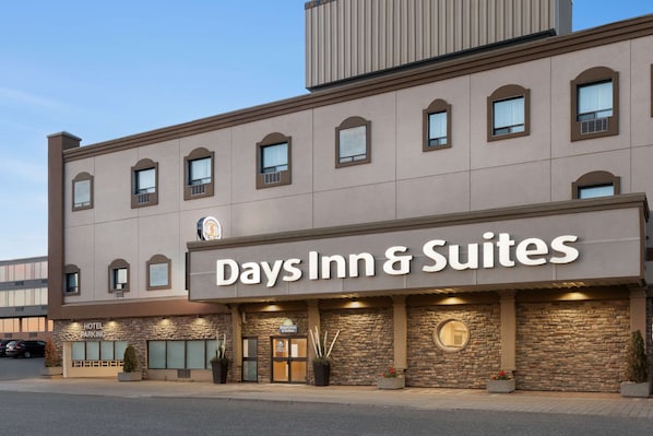 A Days Inn & Suites building with a stone facade, large windows, and a visible hotel parking area.