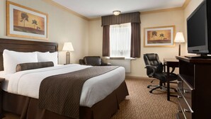 A hotel room with a large bed, a desk, a chair, a television, and two framed pictures on the wall. - Days Inn & Suites by Wyndham Sault Ste. Marie ON (Sault Ste. Marie)