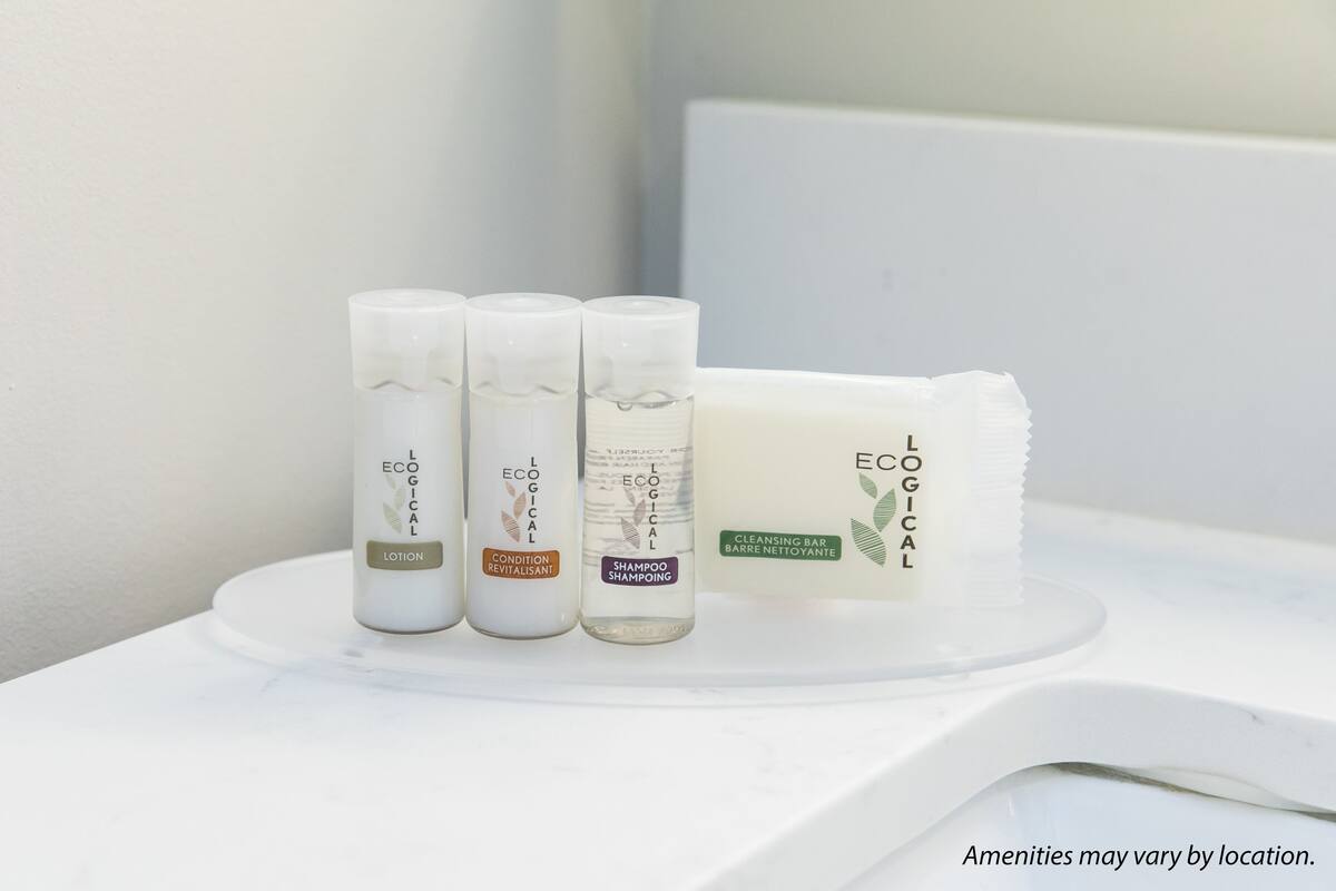 Ein Badezimmer mit einem weißen Waschbecken und drei Produkten von L'ECÔGICAL: Lotion, Conditioner und Shampoo.