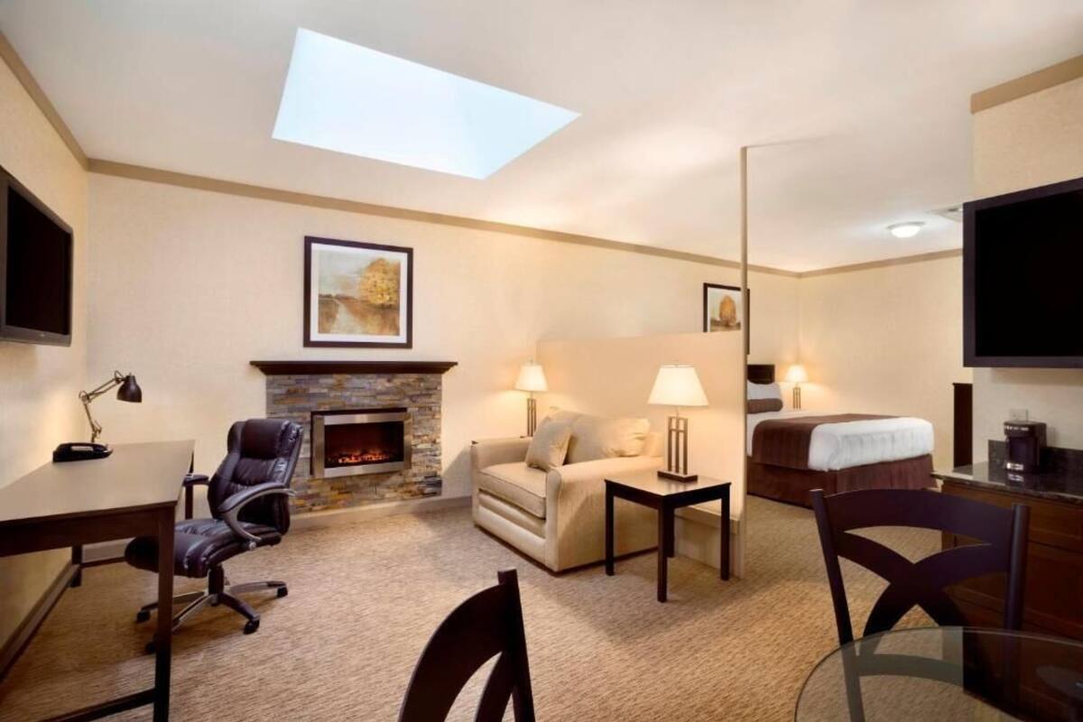 Ein Hotelzimmer mit Kamin, einer Couch, einem Bett, einem Schreibtisch und einem Fernseher.