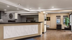 A reception area with a reception desk, a clock, and a plant. - Days Inn & Suites by Wyndham Sault Ste. Marie ON (Sault Ste. Marie)