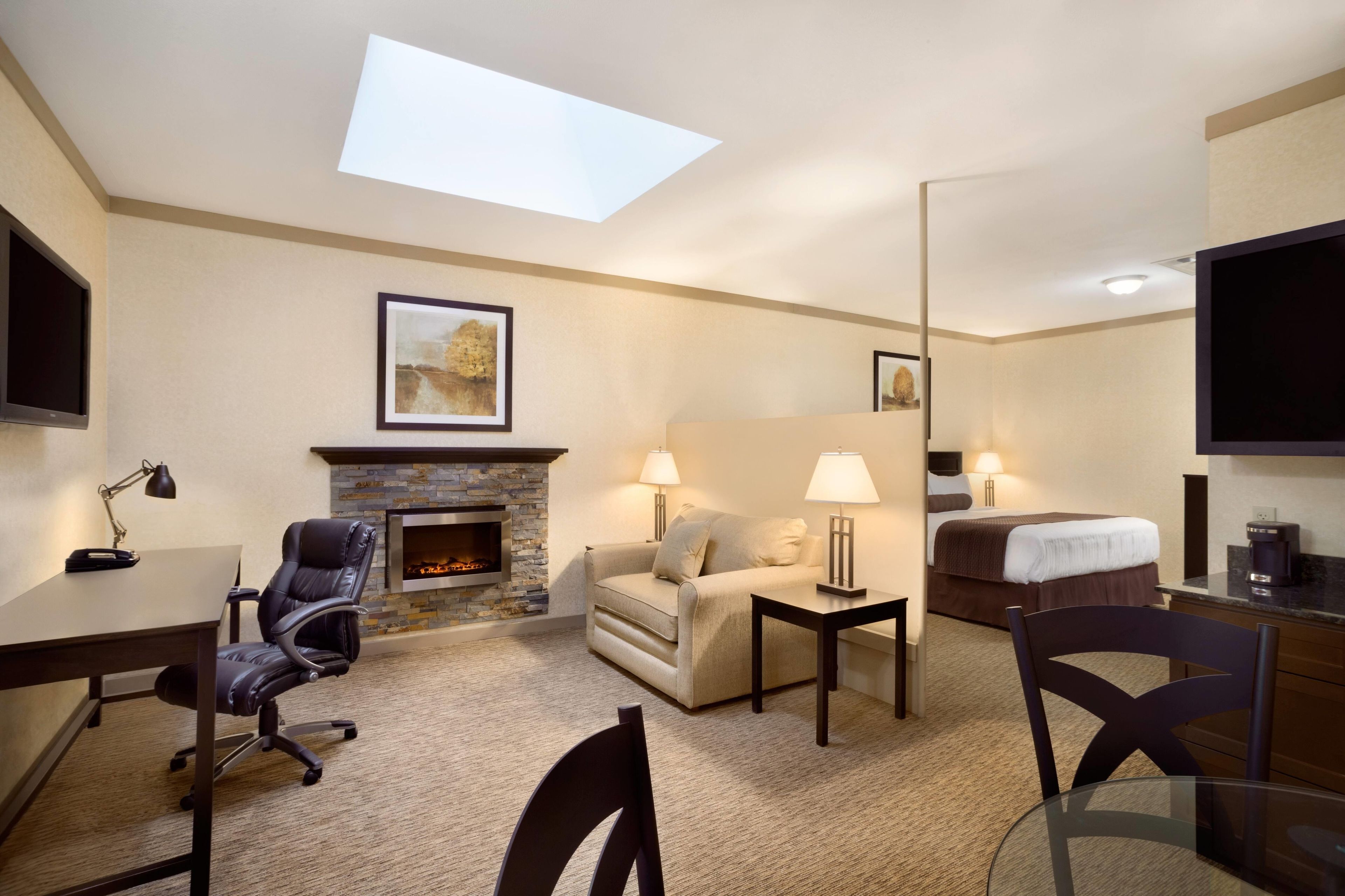 Habitación de hotel con chimenea, sofá, escritorio, silla, cama y televisor.