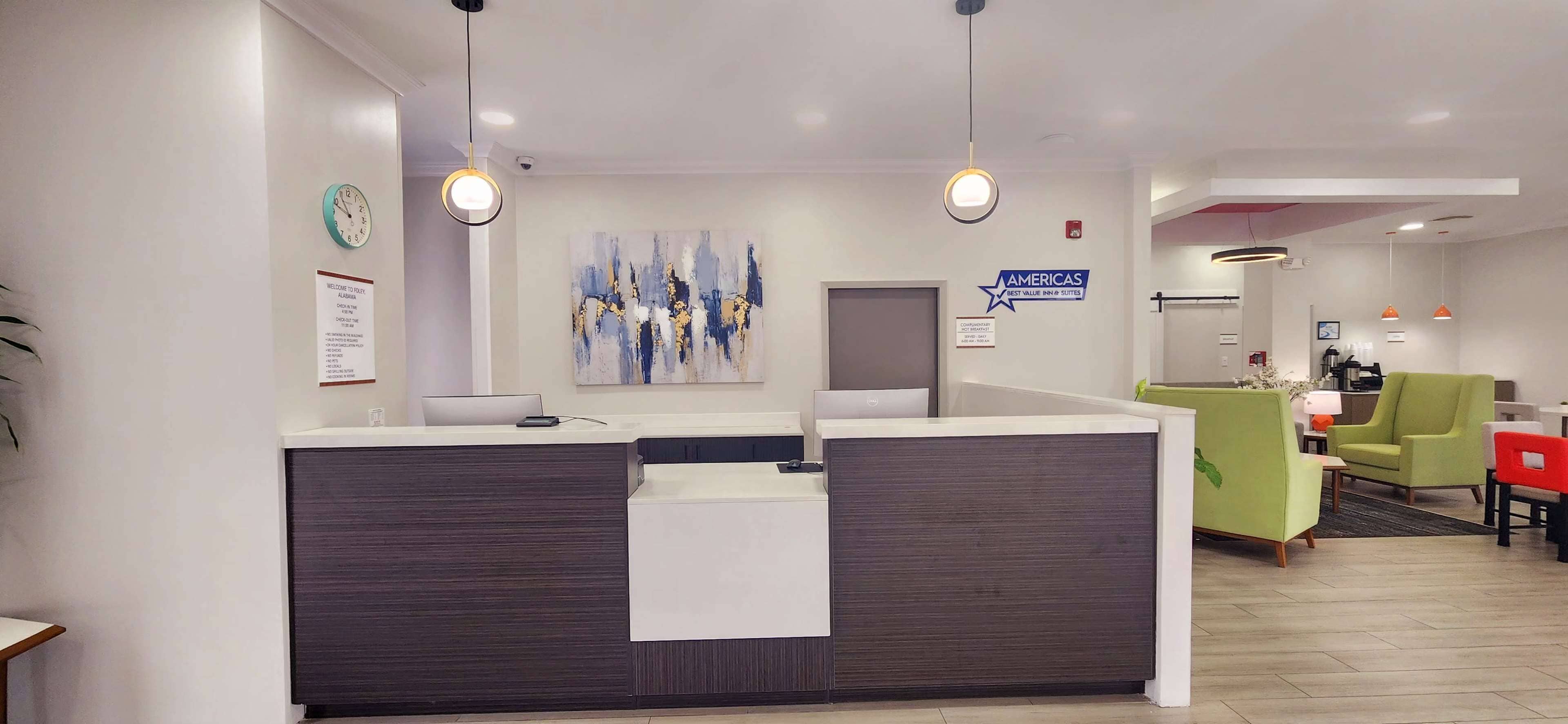 A reception area with a dark wood reception desk, a clock, and a blue sign indicating 'AMERICAS'.