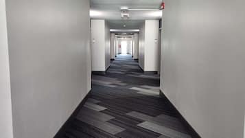 A long, narrow hotel corridor with a patterned carpet and white walls.