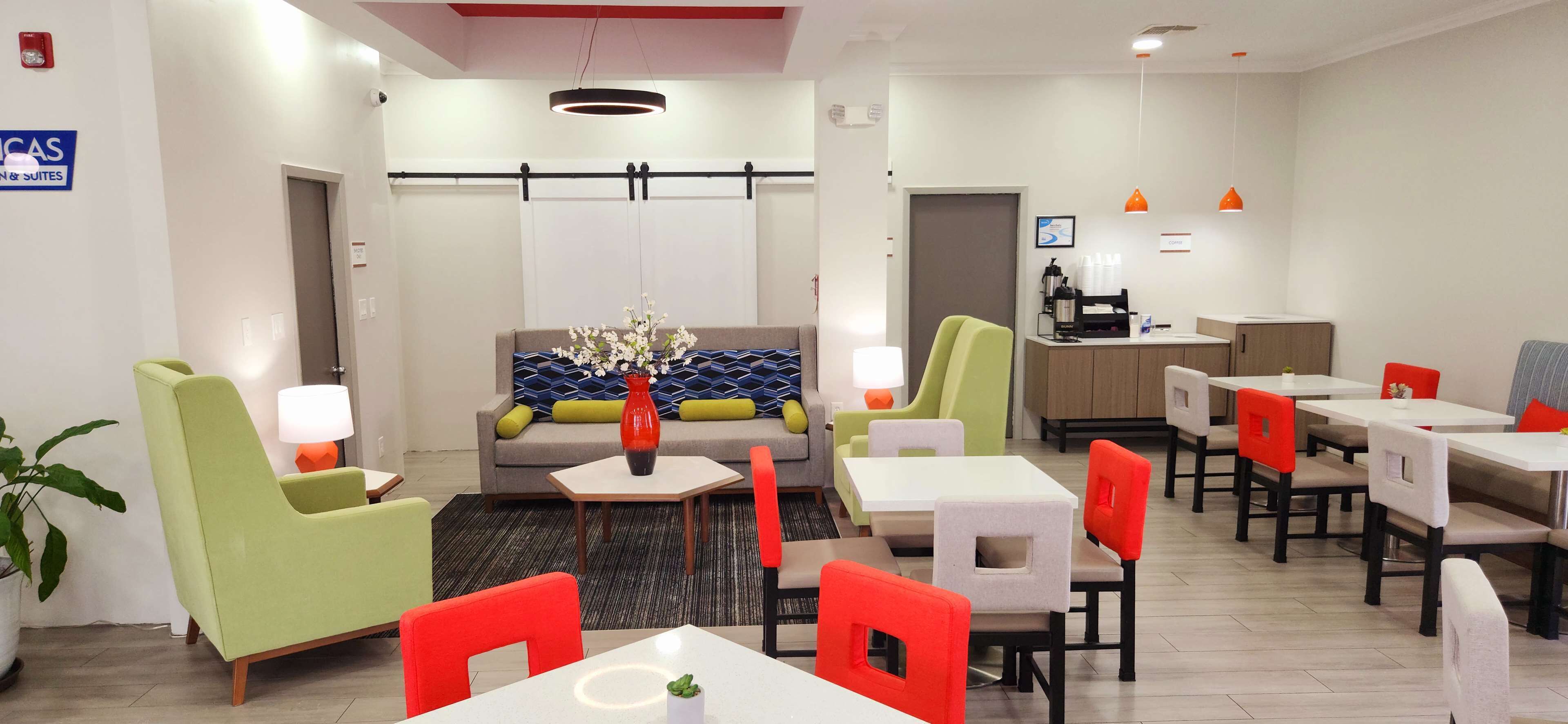 A modern hotel lobby with a sofa, chairs, tables, and a coffee station.